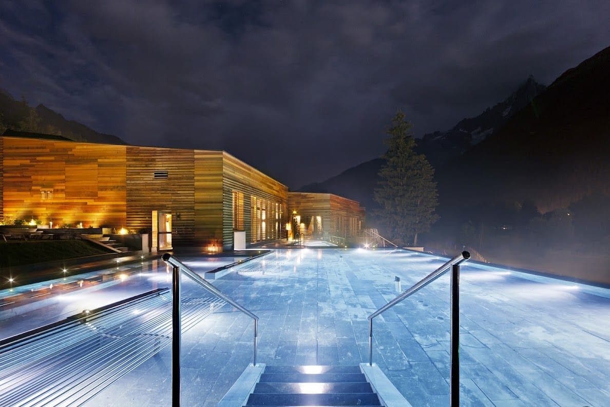 Le bassin extérieur de QC Terme Chamonix éclairé à la nuit tombée