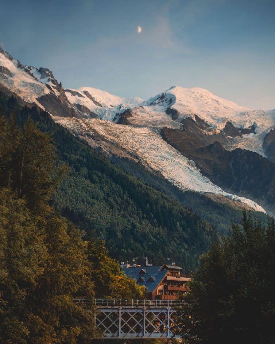 The Bossons glacier above the forest and a chalet in the Chamonix valley