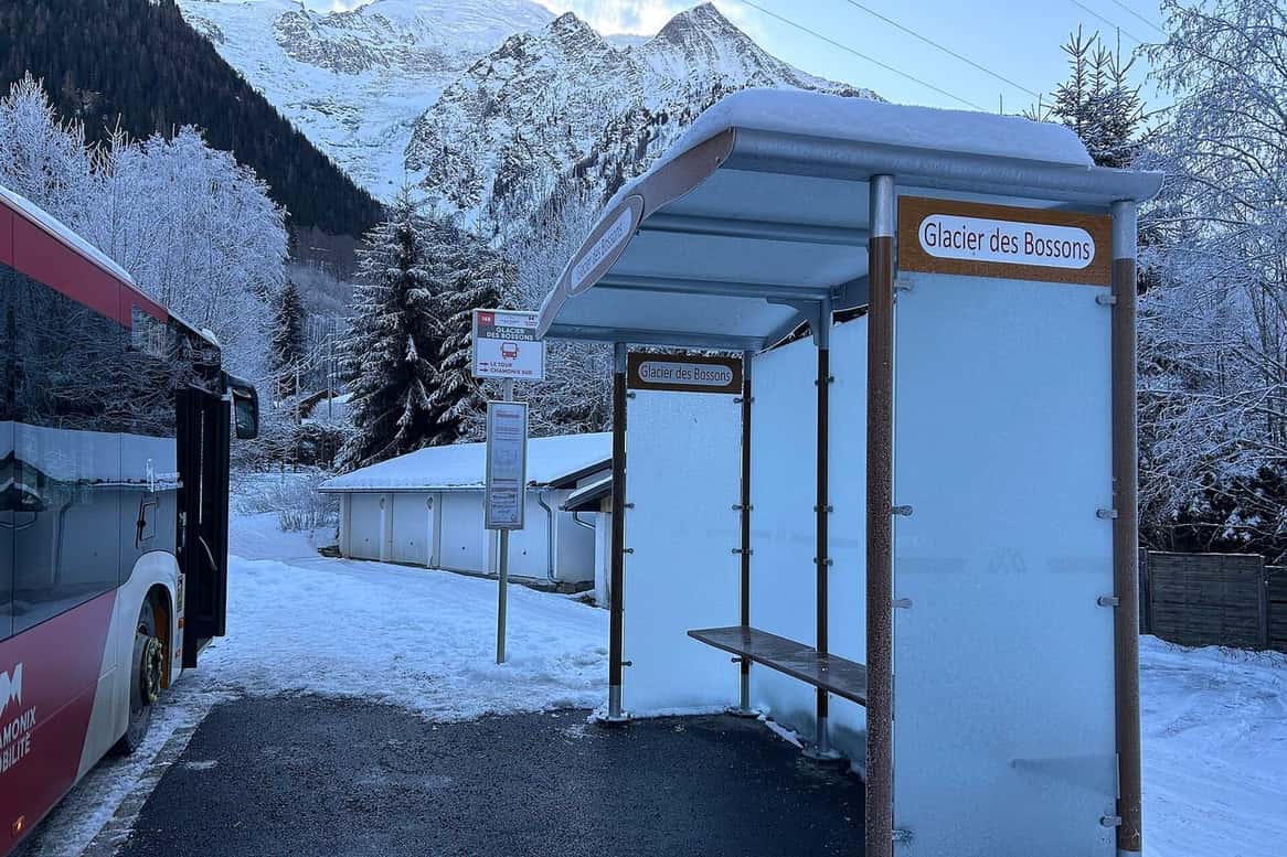 A Chamonix Mobilité bus shelter at the Glacier des Bossons stop, under fresh snow, a local bus pulling in