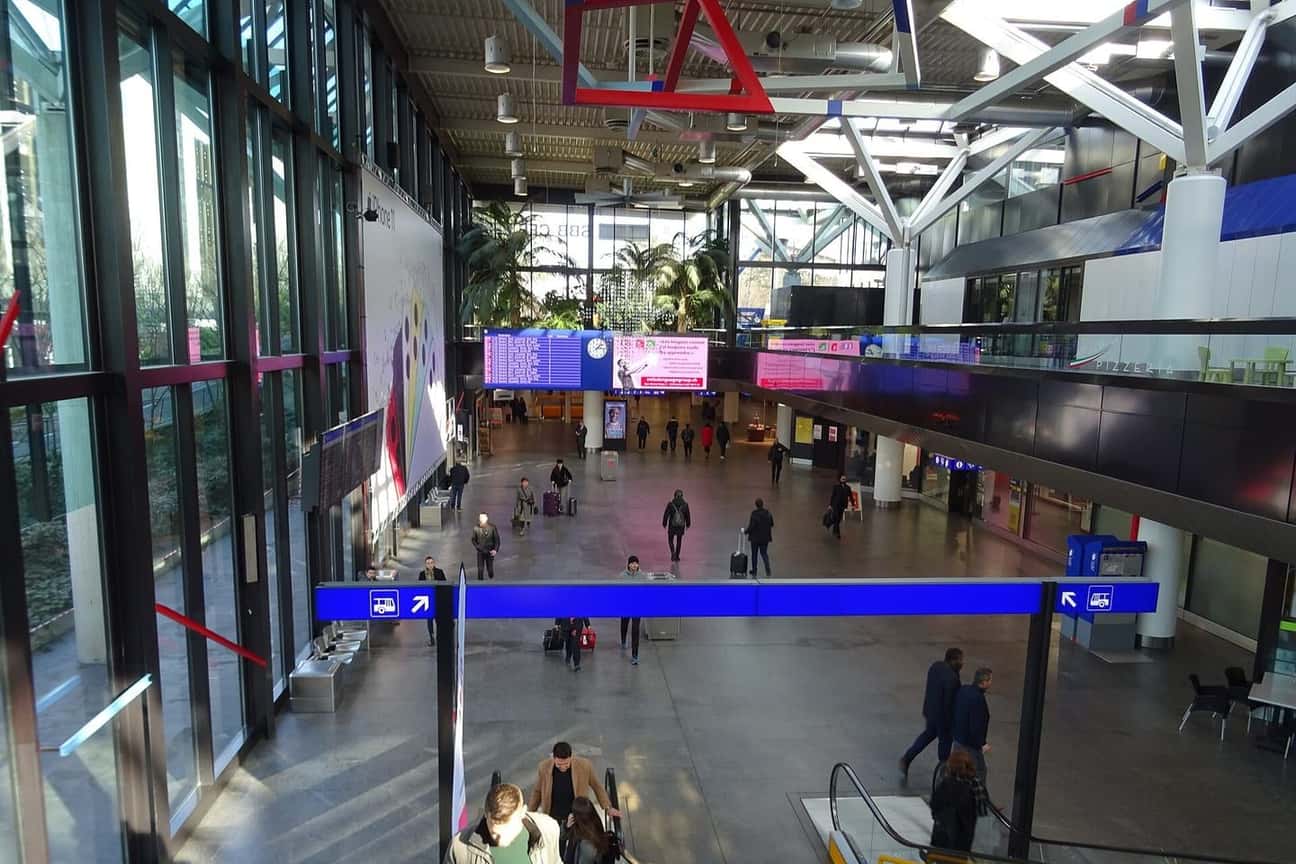 The main hall of Geneva airport, with travellers walking past the departure boards and shops