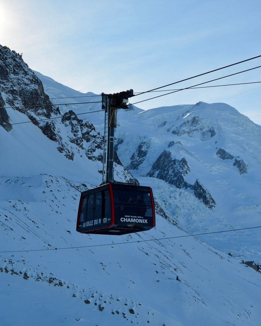 Cabine du téléphérique de l'Aiguille du Midi au-dessus des pentes enneigées, dôme du Mont-Blanc au fond