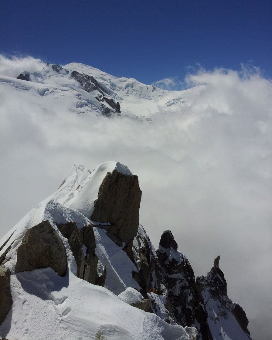Rochers enneigés au-dessus d'une mer de nuages, dôme du Mont-Blanc au fond