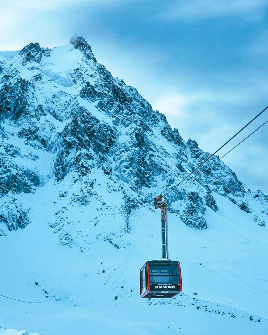 Cable car cabin above snowy slopes, below the granite needles of the massif